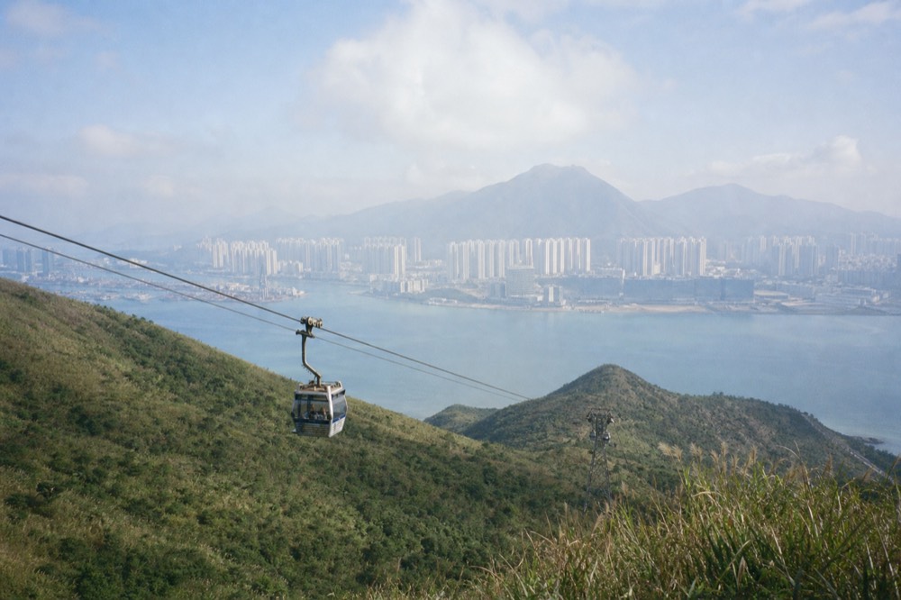 A cable car cabin crossing the green slopes above Nei Lak Shan on the way to Ngong Ping, no text, no logos, no people