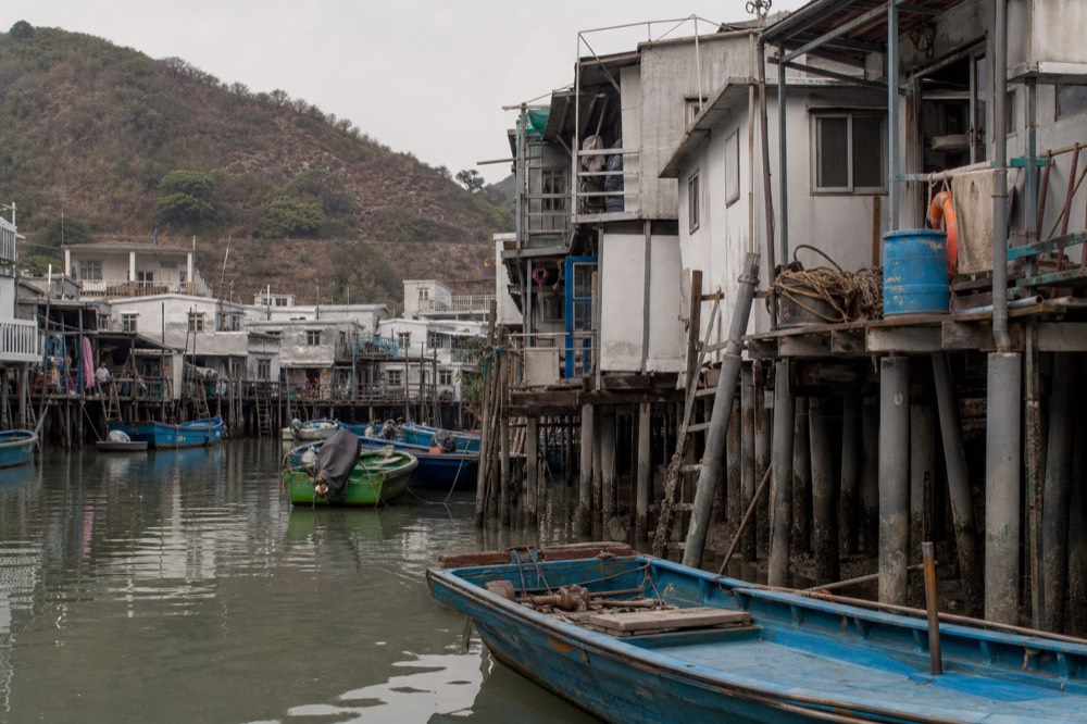Fishing boats moored in Tai O creek beside wooden stilt houses, no text, no logos, no people