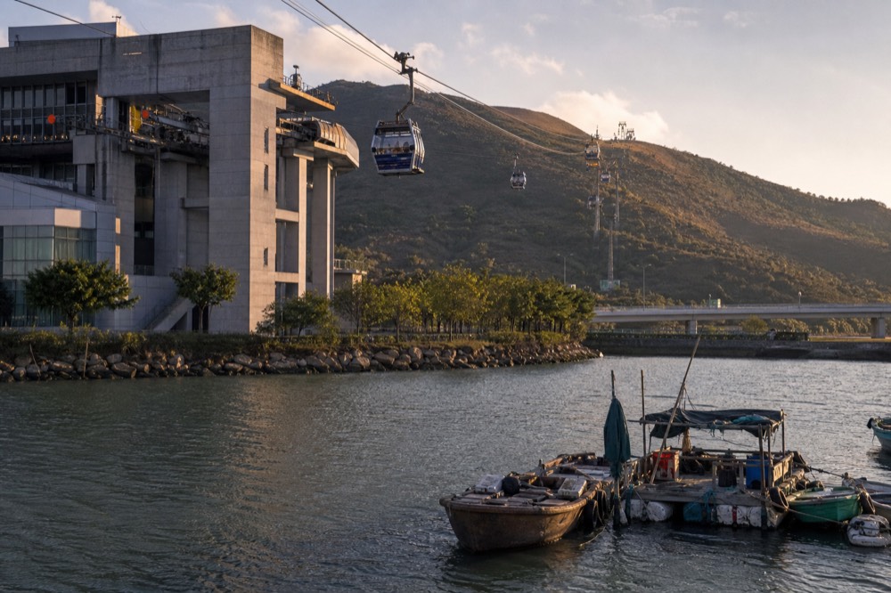 Cable car cabins suspended above the water and hills on the Lantau ropeway, no text, no logos, no people