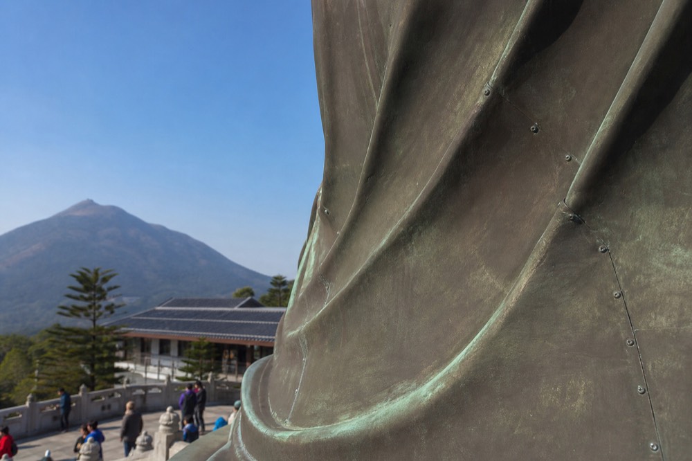 Bronze robe detail of the Tian Tan Buddha statue against the sky, no text, no logos, no people