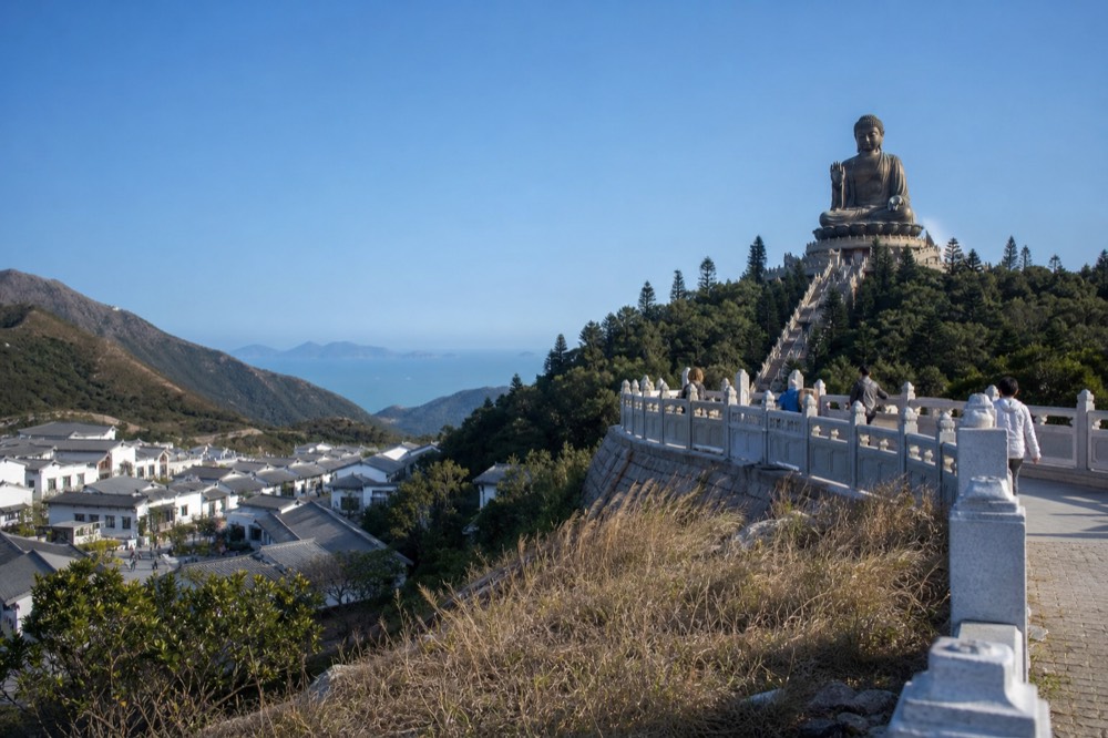 The Big Buddha and surrounding hills under a clear sky with distant sea horizon, no text, no logos, no people