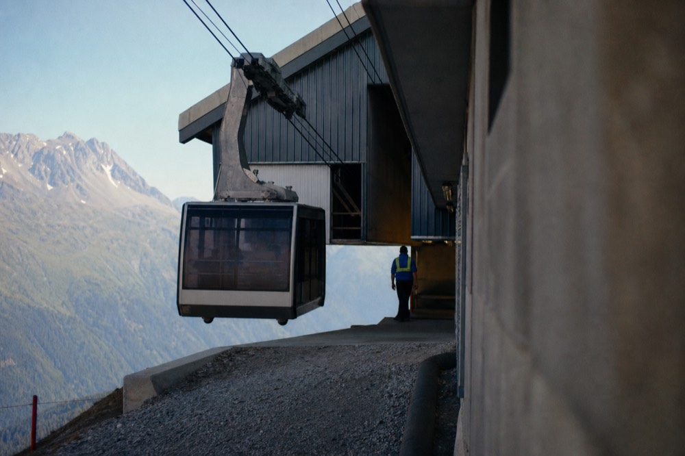 A cable car cabin arriving at a hilltop terminal building on the Ngong Ping plateau, no text, no logos, no people.