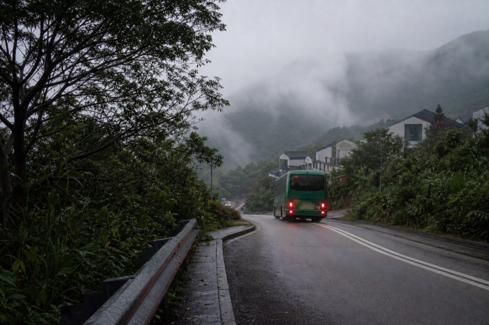 Bus 23 on winding Tung Chung Road with misty hills, no text, no logos, no people