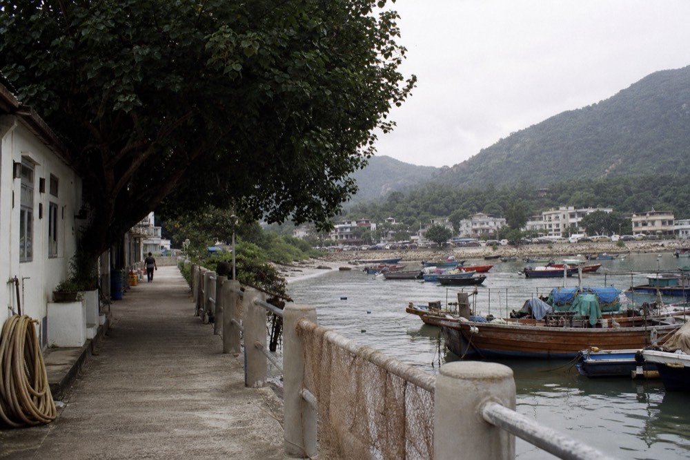 Small waterfront town with low buildings, a promenade and moored boats, no text, no logos, no people