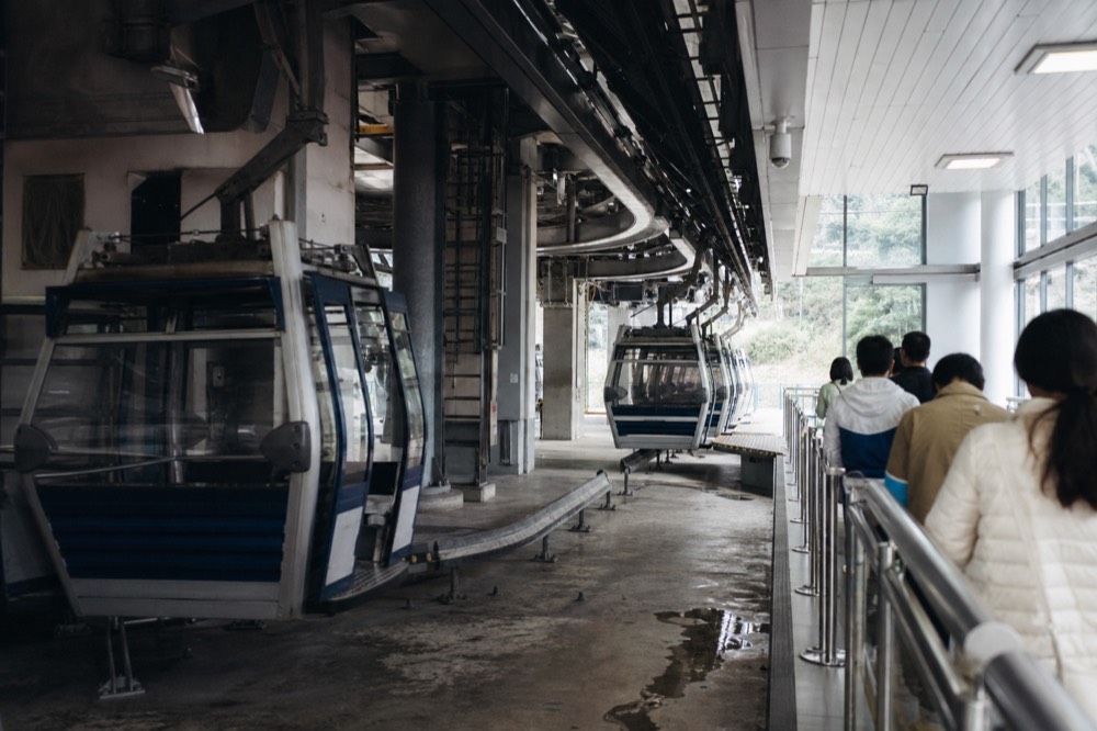 Tung Chung cable car terminal boarding platform with cabins arriving, no text, no logos, no people.