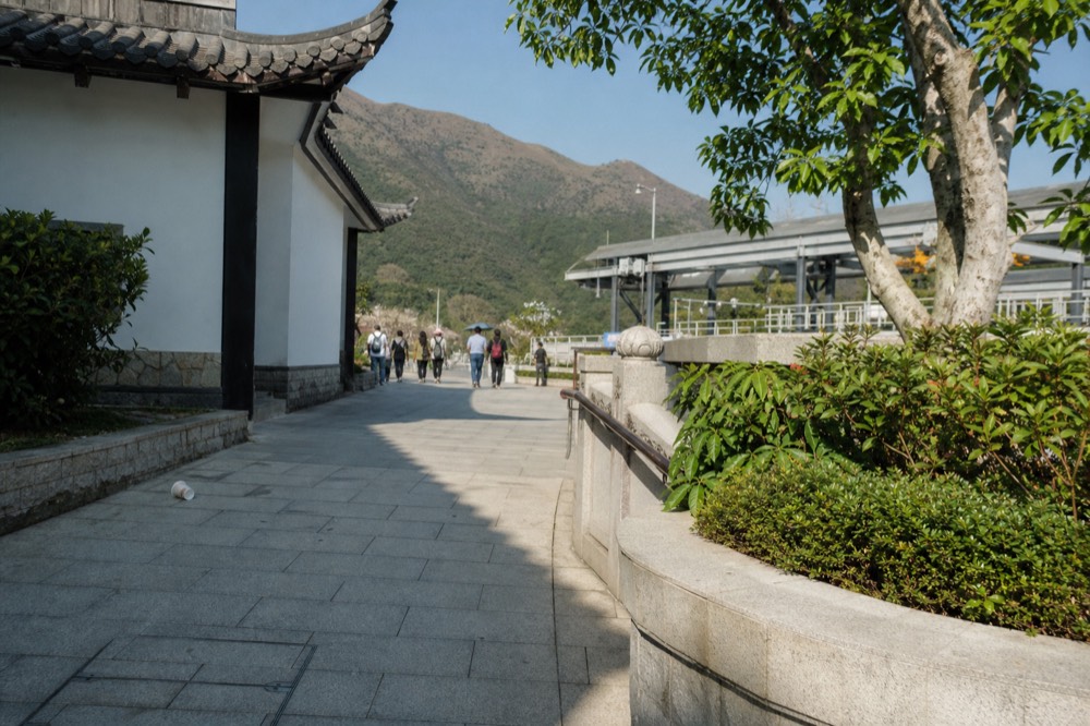 Ngong Ping Village walkway with traditional-style buildings on the plateau, no text, no logos, no people.