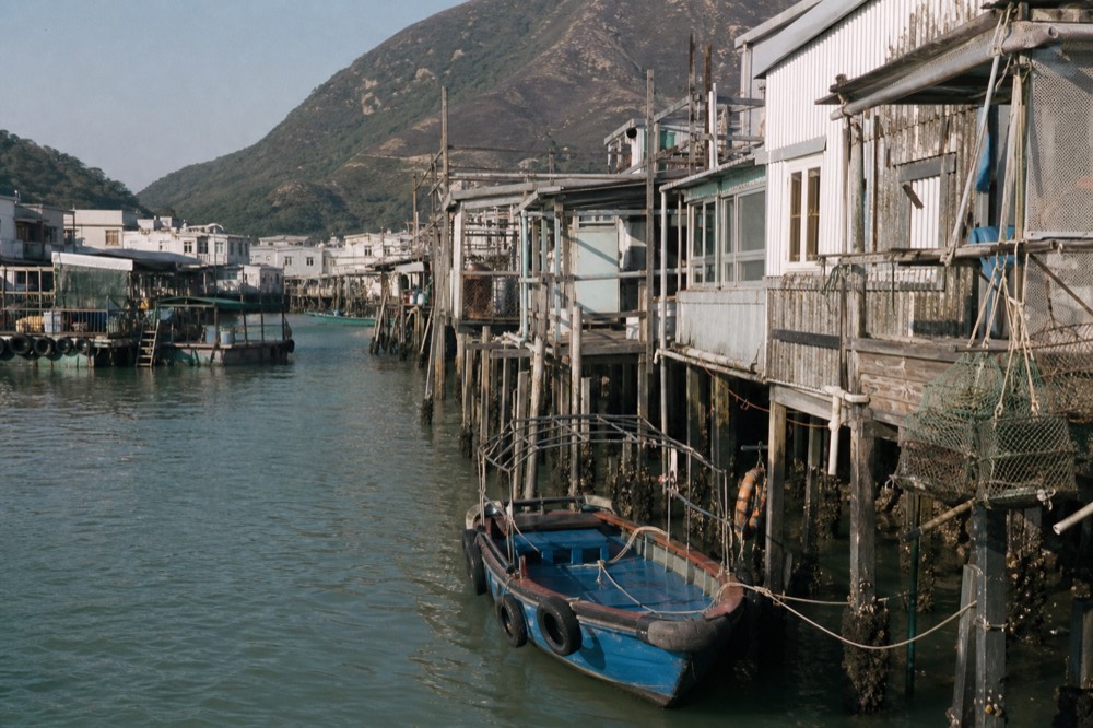 Stilt houses standing over the water at Tai O fishing village in afternoon light, no text, no logos, no people.