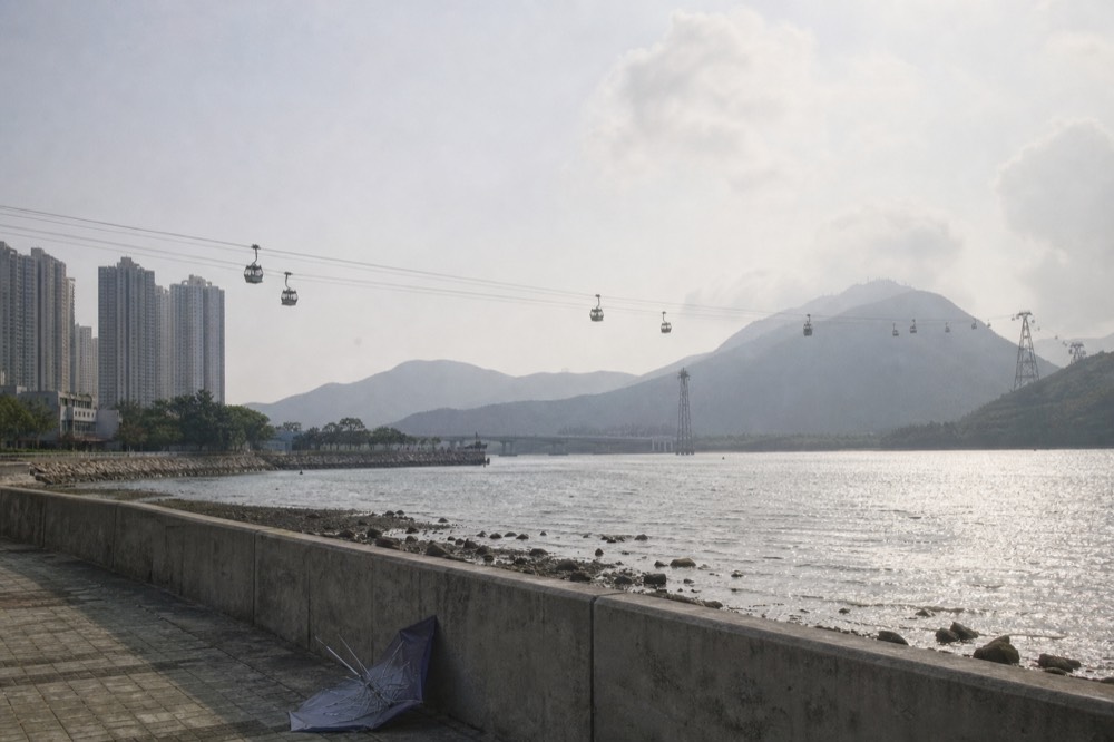 Cable car cabins crossing Tung Chung Bay toward Lantau's hills, no text, no logos, no people