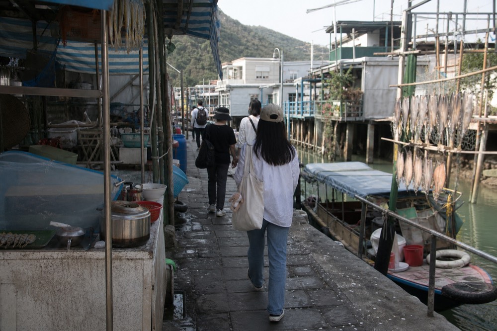 Visitors walking through the main street of Tai O fishing village between stilt house views, no text, no logos, no people